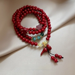 Detail of red beaded bracelet with Fu pendant, chili charm and a 4cm tassel detail