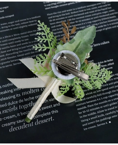 Detail of cream silk boutonniere back with metal safety pin and clip for wedding suits