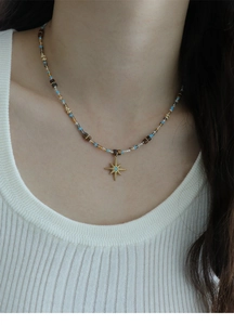 Detail of beaded star necklace with blue crystals and tiger eye stones on model