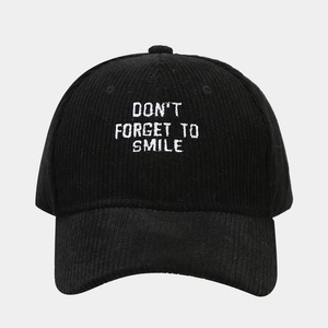 Detail of white embroidered slogan on black corduroy baseball cap texture