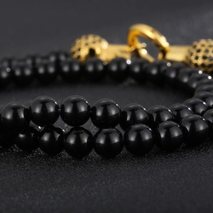 Macro shot of polished black beads and gold clasp with pavé black stones on a skull bracelet