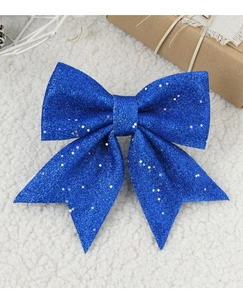 Detail showing a large sparkling blue sequined bow ornament on a white plush background