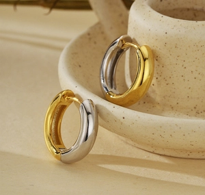 Macro shot of two-tone gold and silver polished hoop earrings on a ceramic pot