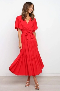 Detalle del vestido maxi rojo con cuello en V, falda a capas y lazo en la cintura