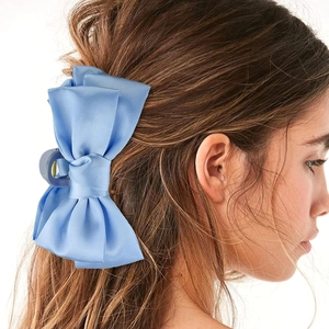 Side view of a large light blue satin bow hair claw clip worn on a woman's head