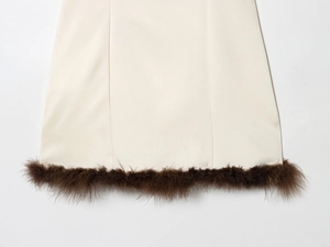 Close-up of cream satin dress hem featuring fluffy brown feather trim and soft texture