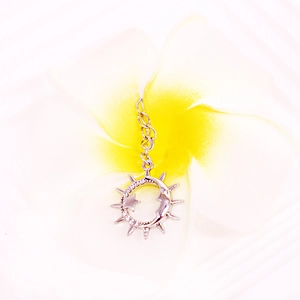 Detail of silver crescent moon and sun nipple ring pendant with cubic zirconia inlay