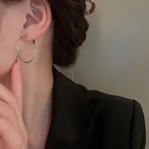 Boucles d'oreilles créoles argentées minimalistes portées par un mannequin style chic