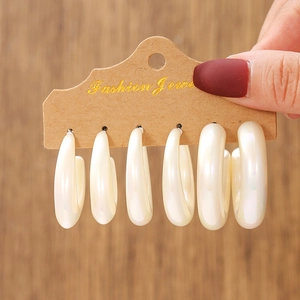 Close-up of six pairs of cream pearl hoops in graduated sizes on a display card