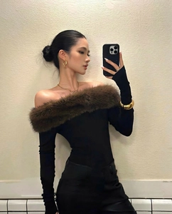 Close-up of model wearing gold C-shaped earrings with brown faux fur trim top