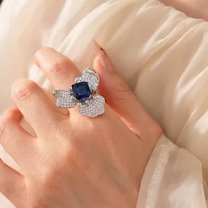 Elegant silver flower ring with square blue zircon and pavé diamonds worn by model