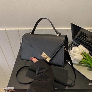 Close-up of black crocodile texture leather bag with elegant gold metal lock detail