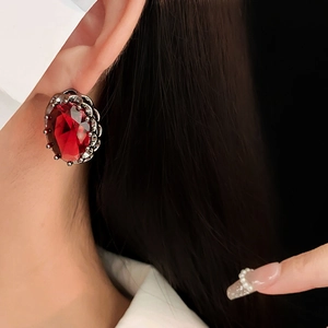 Close-up of vintage red oval zircon earring with dark metal details on model's ear