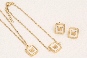 Close-up of golden square jewelry set with white butterfly relief and textured surface