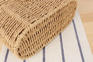 Detailed close-up of beige straw woven texture and artisan craftsmanship on women's bag