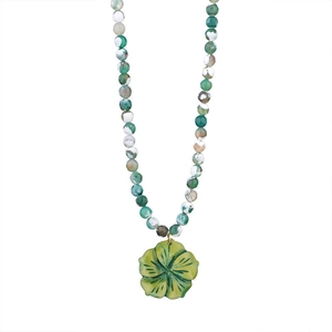 Macro detail of natural stone beads and green floral pendant on Cuban chain necklace