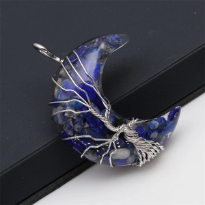 Detailed close-up of crescent moon resin pendant with stone inlay and tree of life wire wrap