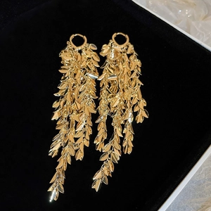 Boucles d'oreilles pendantes à feuilles dorées présentées sur un écrin en velours noir