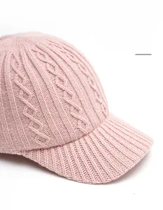 Detail of pink knitted baseball cap showing chunky cable knit texture and foldable brim