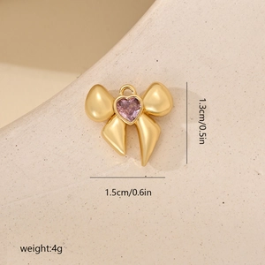 Detalle de colgante de lazo dorado con gema de corazón púrpura y medidas reales