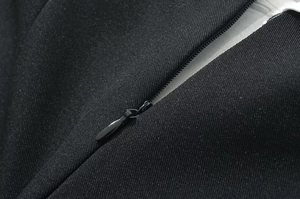 Detailed close-up of a hidden zipper on a black fashion dress with woven fabric texture