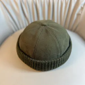 Deep green retro docker hat in canvas and knit mix on a soft beige background