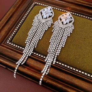 Detailed close-up of zircon tassel earrings on olive green velvet and vintage frame