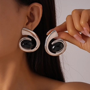Gros plan de boucles d'oreilles spirales argentées avec pierre ovale noire sur mannequin