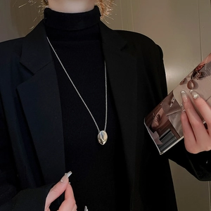 Minimalist silver oval pendant necklace styled on a black blazer for a premium look