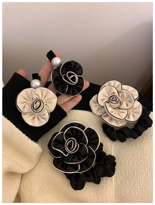 Detailed view of elegant black and white camellia hair clips with pearls and satin scrunchies