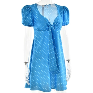 Detail of blue polka dot dress featuring puff sleeves and V-neck with bow tie detail