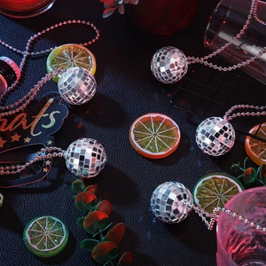 Flat lay of six silver disco ball necklaces with mirror mosaic tiles on a dark party surface