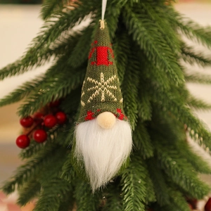 Close-up of green knitted Christmas gnome ornament with reindeer pattern on tree branch