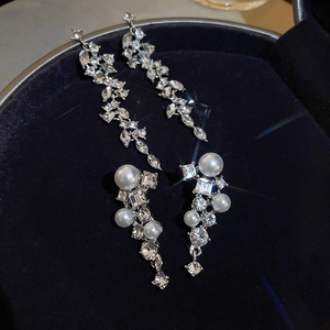 Macro shot of sparkling rhinestone leaf tassels and pearl drops on blue velvet