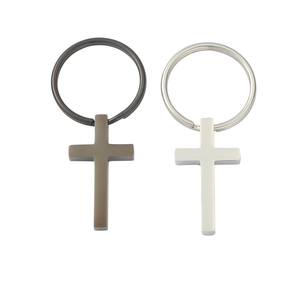 Detail view of matte gunmetal and silver cross pendants on minimalist keychains