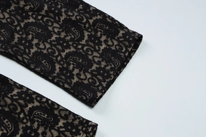 Detailed close-up of intricate black floral lace texture on pink lining of a bodysuit
