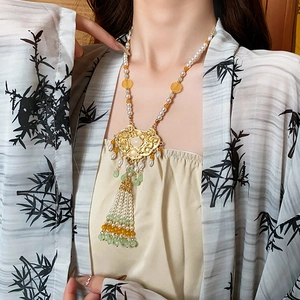 Detail of Chinese tassel necklace featuring gold lock charm and elegant white pearls