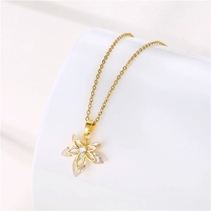 Détail macro du collier pendentif feuille avec zircons clairs sur chaîne dorée