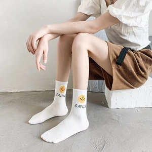Detail of white cotton crew socks with yellow smiley face and SMILE text design