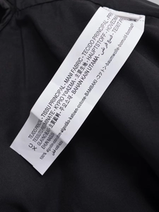 Detailed close-up of the care label showing 100% cotton material on black casual hoodie