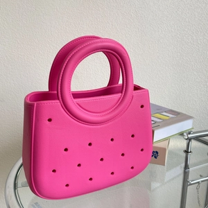 Détail du sac de plage EVA rose vif avec motif ajouré sur une table en verre