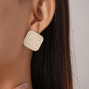 Elegant gold square stud earrings with pave-set crystals shown on a model's ear