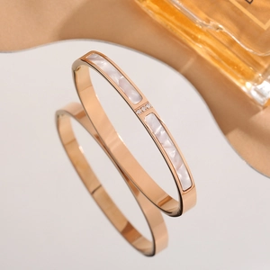 Macro detail of rose gold bracelet with white mother of pearl inlay and three tiny diamonds