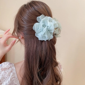 Detail einer großen minzgrünen Blumen-Haarklammer an einer eleganten Frisur