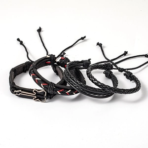 Detail of four-piece black leather bracelet set with guitar charm and braided hemp ropes