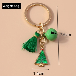 Christmas tree keychain with green tassel and bell on light pink background