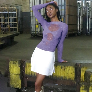 Détail d'un body en maille violette avec strass et manches longues sur un mannequin en entrepôt