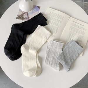 Flat lay of breathable mesh knit crew socks in neutral colors on a minimalist desk
