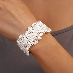 Detailed view of a wide silver cuff bracelet with intricate hollow flower patterns on wrist