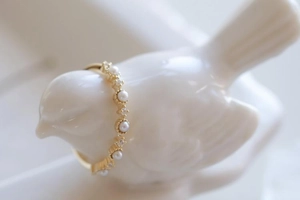 Close-up of gold ring with freshwater pearls and small diamonds on a white bird prop